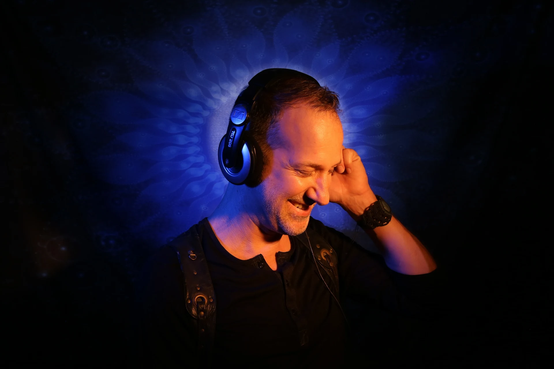 Rebel Rob, electronic music producer and DJ, wearing headphones under blue stage lighting